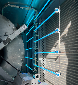 Illuminated blue UV-C lamps installed inside a school HVAC air handling unit targeting cooling coils