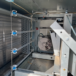 Technician inspecting a school HVAC air handling unit prepared for UV-C lamp installation